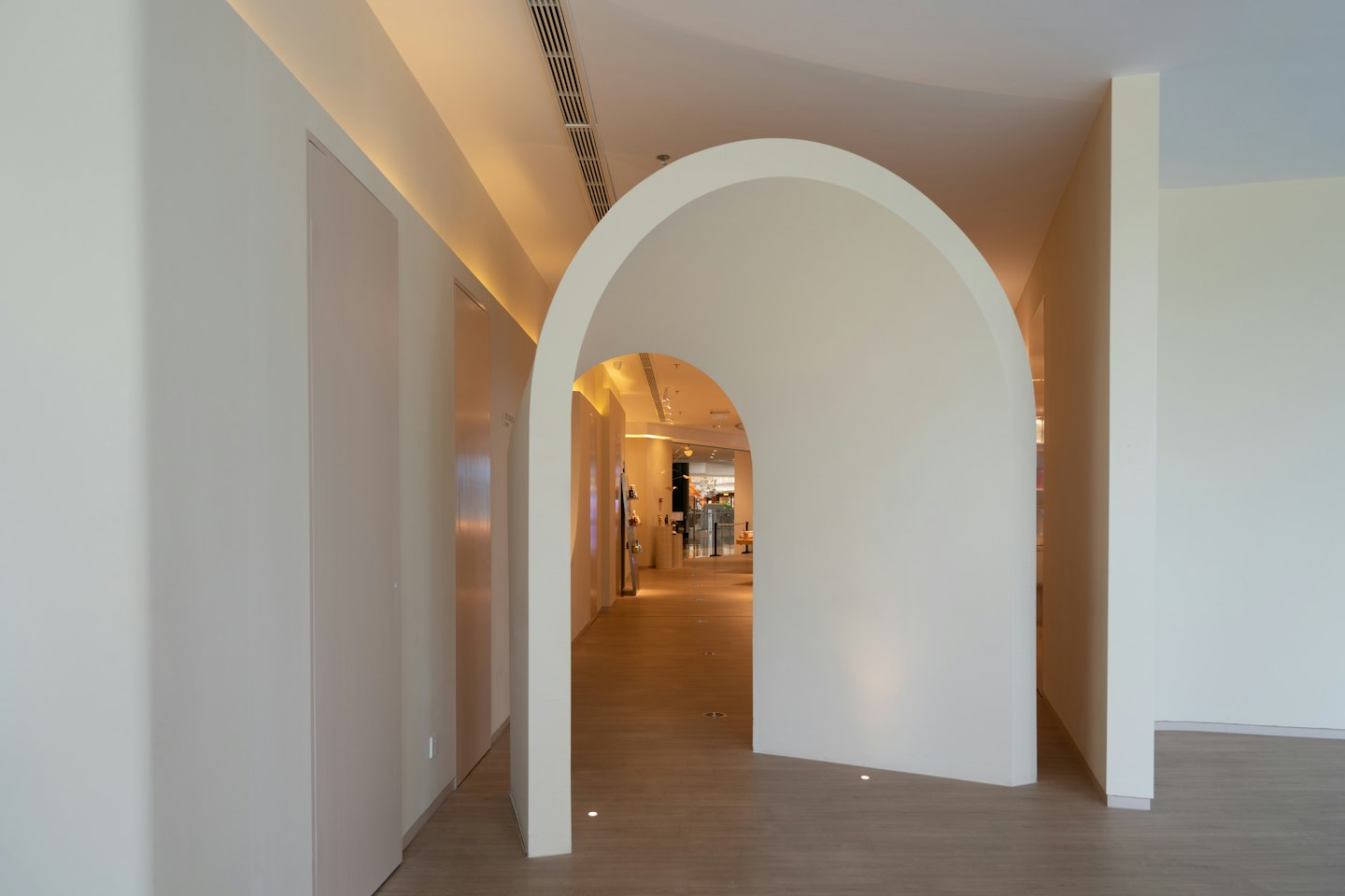 A white arched hallway opening into a bright room