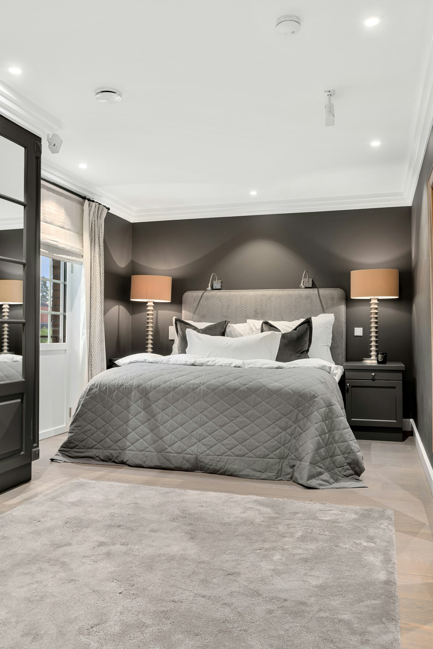 A master bedroom in soft grey with a curved headboard
