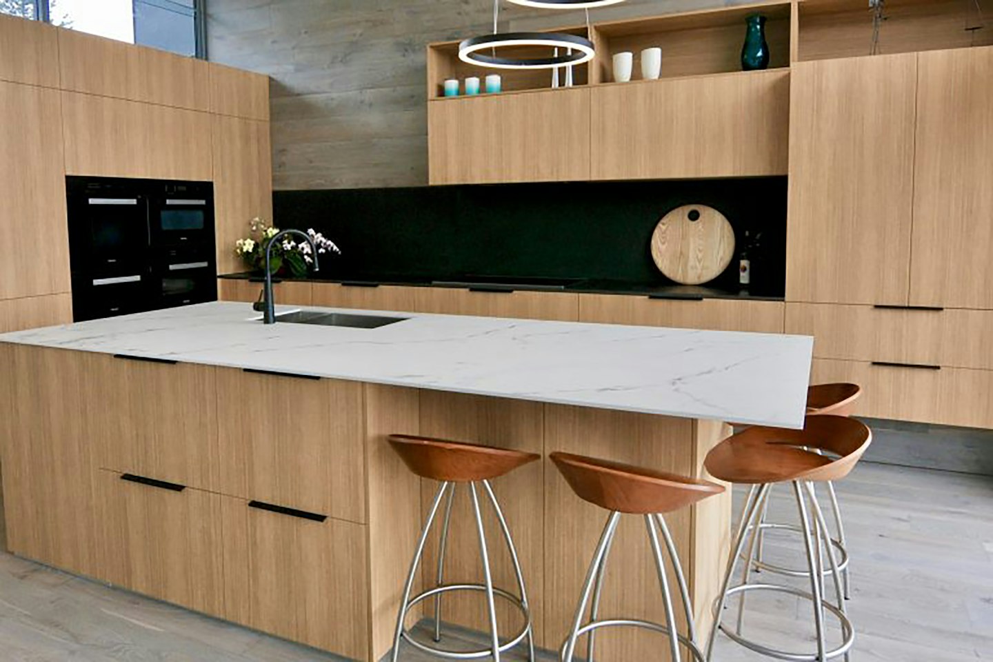 A kitchen island in pale stone with oak stools
