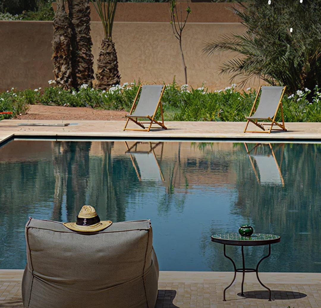 Villa YAH, Marrakech: a linen pouf and straw hat beside the pool